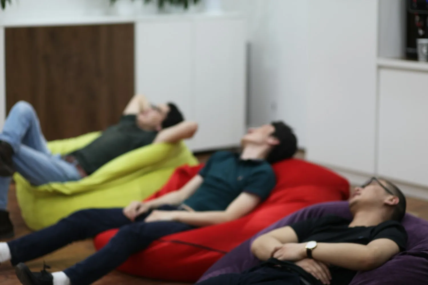 Salariés détendus allongés sur des poufs colorés dans un espace convivial dédié au bien-être au travail